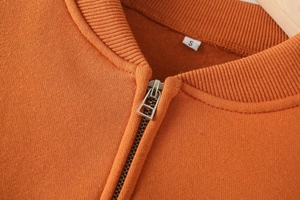 Detail of ribbed collar and metal zipper on orange bomber jacket fleece sweatshirt