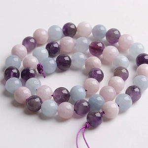 Macro detail of polished natural tiger eye and amethyst round beads on silk thread