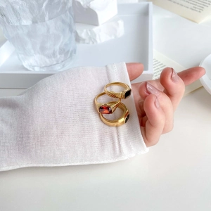 Close-up of three gold rings with red oval gem, black square stone and spiral texture