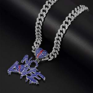 Detailed view of NO LOVE heart pendant with blue rhinestones on a silver Cuban chain
