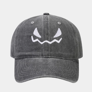 Macro detail of Halloween pumpkin face embroidery on vintage washed cotton baseball cap