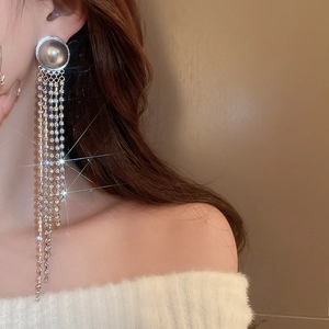 Macro view of long silver tassel earrings with grey pearls and shimmering rhinestones