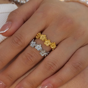 Close-up of gold and silver stainless steel flower rings on model fingers