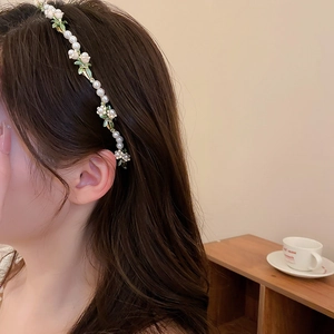 Detail of elegant lily of the valley headband with white pearls and enamel flowers