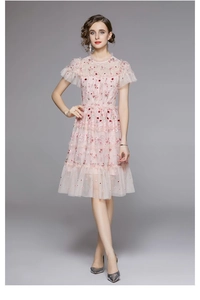 Détails d'une robe en tulle rose avec broderies florales et manches courtes à volants