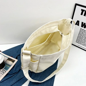 Minimalist white canvas messenger bag featuring multiple internal compartments for students