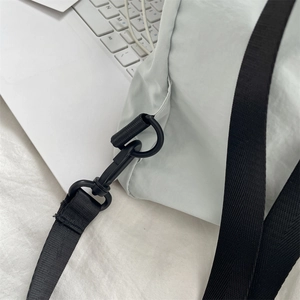 Detail view of the black nylon strap and matte swivel hook on a white drawstring backpack
