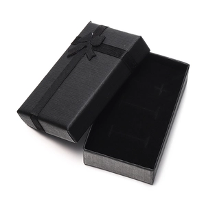 Macro shot of a black textured jewelry box with ribbon bow and soft black lining