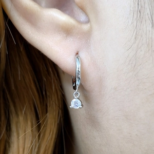 Close-up of S925 silver hoop earrings with clear round cubic zirconia pendant on ear