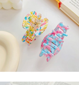 Detail of floral and gradient acetate hair claws on a desktop with a French book