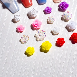 Detailed view of 3D resin roses for nail art in multiple colors on a textured surface