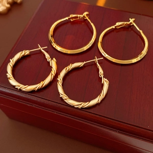 Close-up of golden sleek and frosted twisted hoop earrings on a wooden jewelry case