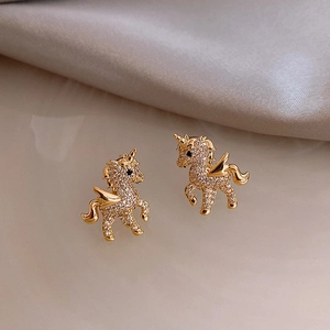Detail of gold-plated unicorn stud earrings with shimmering white cubic zirconia stones