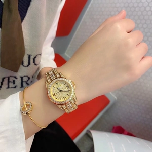 Close-up of golden diamond-encrusted watch and matching bracelet on a female wrist