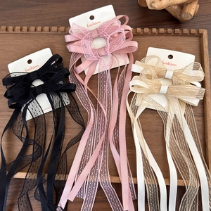 Detailed set of three lace bow hair clips in black, pink and beige on a wooden tray