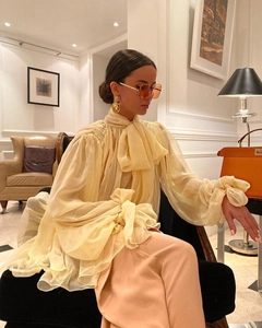 Close-up of light yellow chiffon blouse featuring a bow neck tie and pleated cuffs