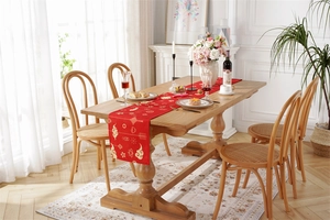 Close-up of festive red table runner with golden patterns on a rustic wooden dining table