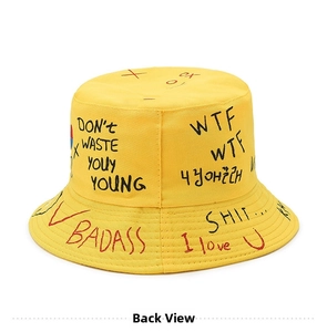 Detail of yellow bucket hat featuring creative graffiti prints and artistic handwritten text