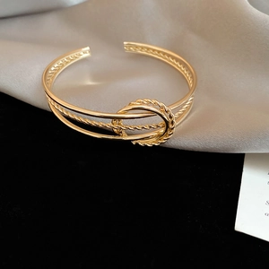 Close-up of gold twisted knot bangle featuring multiple bands and rope textured details