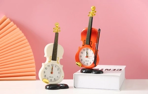 Dettaglio di orologi da tavolo a forma di violino color crema e legno su sfondo rosa