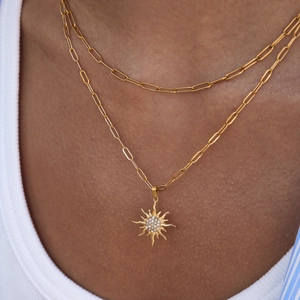 Dettaglio di una collana dorata a due strati con un pendente a sole e brillantini