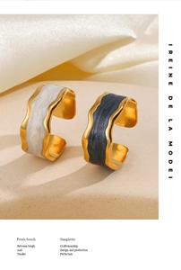 Detail of wavy open rings in gold plating with black and white enamel textures
