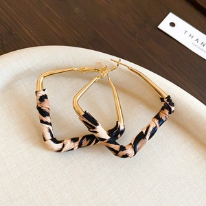 Close-up of geometric leopard print earrings with gold metal frame on a display tray