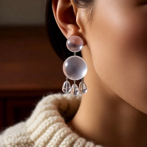 Detail of lavender resin geometric earrings with water-drop charms on a female model