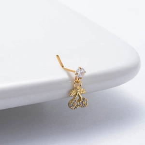 Detailed close-up of a gold L-shaped nose stud featuring a crystal cherry pendant charm