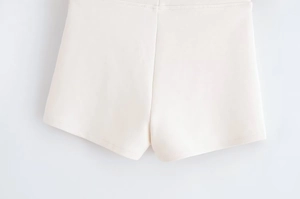 Detail shot of beige knit shorts showing high-quality elastic fabric and precision stitching