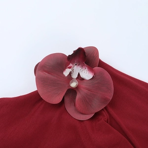 Close-up of wine red knitted top with a detailed magenta faux orchid flower attachment