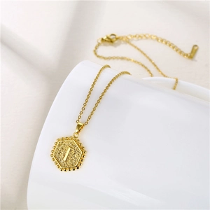 Close-up of golden stainless steel hexagonal necklace featuring an engraved letter I pendant