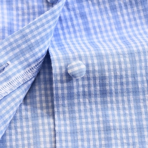 Detailed macro view of blue and white plaid fabric texture with a fabric-covered button