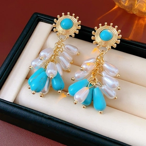Detailed macro of vintage gold earrings with pearls and turquoise in a leather box