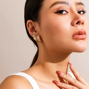 Detailed view of polished golden bow earring on model for an elegant minimalist look