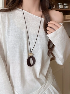 Macro detail of acrylic resin pendant necklace featuring vintage dark brown oval charm
