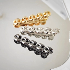 Three-color metal hair clips in chain design on a reflective mirror surface