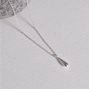 Close-up of a silver teardrop pendant necklace on a natural stone minimalist background