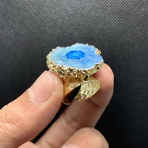 Detalle macro de anillo de cristal azul con banda ancha ajustable chapada en oro de 14K