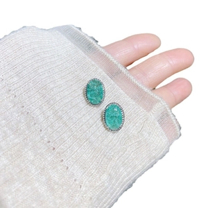 Retro green cracked crystal stud earrings with silver beaded edges shown on hand
