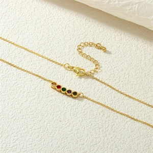 Detail of 18K gold-plated necklace featuring five vibrant round colored gemstones