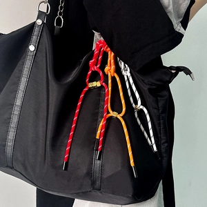 Detail of colorful woven nylon cord bag accessory with gold metal charm engraved with M