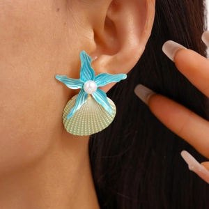 Detail of beach style starfish earring with blue paint finish and white pearl on ear
