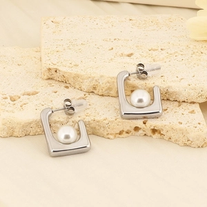 Detail of French vintage square pearl earrings on beige stone and fabric background