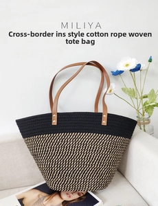 Detail of woven cotton rope tote with contrast colors and leather handles on a sofa