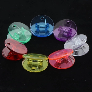 Colorful translucent round plastic clips with hang holes arranged in a ring on black background
