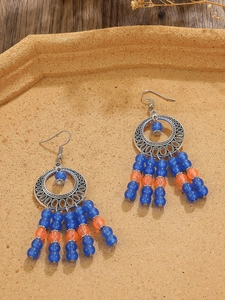 Detail of bohemian drop earrings with silver hollow rings and blue orange beaded tassels