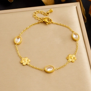 Detailed close-up of gold chain bracelet with oval crystals and floral charms
