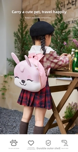 Pink cartoon rabbit backpack with 3D ears on a child model in a sunny outdoor setting