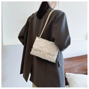 Detailed shot of beige textured tweed bag with golden chain and square lock buckle